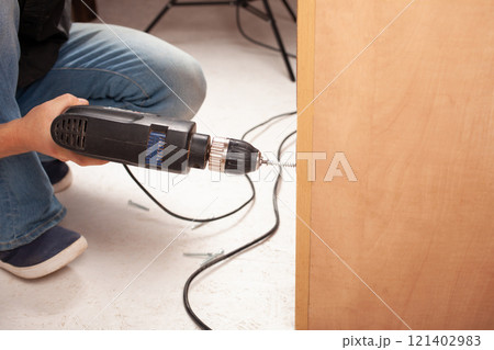 Man twists screw into cupboard 121402983