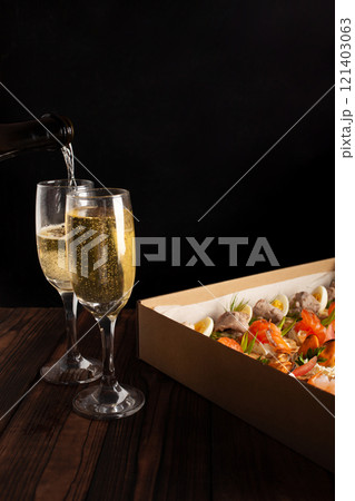 Champagne, tartlets, seafood salads. Cardboard box with food with home delivery. Gift for holiday, party, family dinner. Catering. Delicious snacks. 121403063