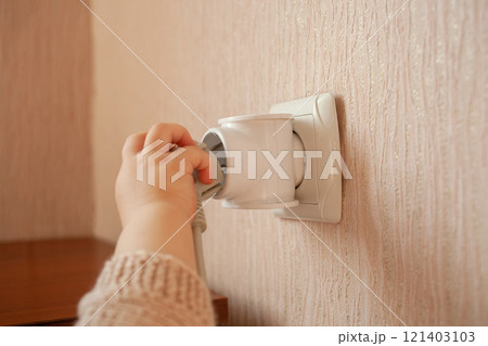 The child plays with an outlet, pulls his hands to it, sticks his fingers. The child is in danger at home. Baby fingers in the socket. The child plays with an outlet, pulls his hands to it, sticks his fingers. The child is in danger at home. Baby fingers in the socket. 121403103