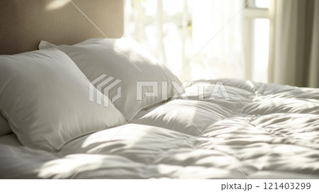 Sunlight illuminating cozy unmade bed with white linens and pillows Sunlight illuminating cozy unmade bed with white linens and pillows 121403299
