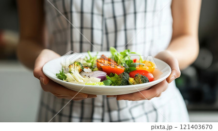 Woman holding a plate of colorful grilled vegetables promoting healthy eating Woman holding a plate of colorful grilled vegetables promoting healthy eating 121403670
