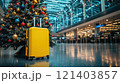 Yellow suitcase standing next to christmas tree in airport terminal symbolizing holiday travel 121403857