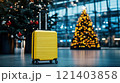 Yellow suitcase stands in airport terminal with christmas trees celebrating holiday season 121403858