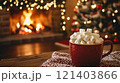 Red mug full of marshmallows warming near fireplace and christmas tree lights 121403866