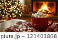 Red mug full of marshmallows warming up by the fireplace during christmas holidays 121403868