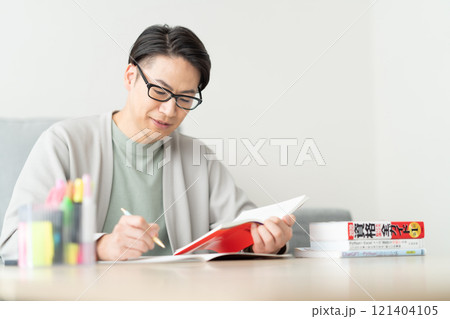 リスキリングのため参考書を確認する30代男性 121404105