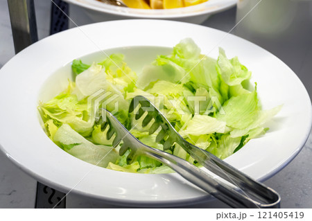 Torn Iceberg Lettuce Leaves in a Large Bowl 121405419