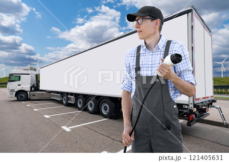 Man with charging plug on a background of electric truck Man with charging plug on a background of electric truck 121405631