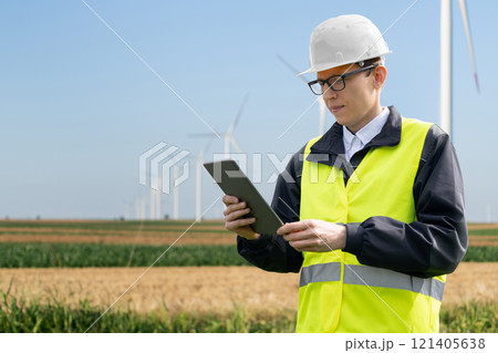 Engineer with digital tablet works on a field of wind turbines 121405638