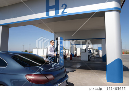 Man holds a hydrogen fueling nozzle on a hydrogen filling station. Refueling car with hydrogen fuel Man holds a hydrogen fueling nozzle on a hydrogen filling station. Refueling car with hydrogen fuel 121405655