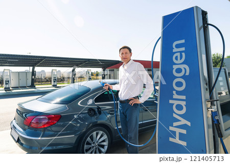 Man holds a hydrogen fueling nozzle on a hydrogen filling station. Refueling car with hydrogen fuel 121405713