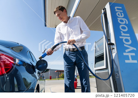 Man holds a hydrogen fueling nozzle on a hydrogen filling station. Refueling car with hydrogen fuel Man holds a hydrogen fueling nozzle on a hydrogen filling station. Refueling car with hydrogen fuel 121405720