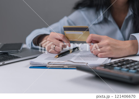 Woman holding credit card and reviewing documents, representing credit approval or financial transactions. Woman holding credit card and reviewing documents, representing credit approval or financial transactions. 121406670