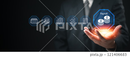Businessman presenting a glowing payroll icon with financial system icons floating in the air. Businessman presenting a glowing payroll icon with financial system icons floating in the air. 121406683
