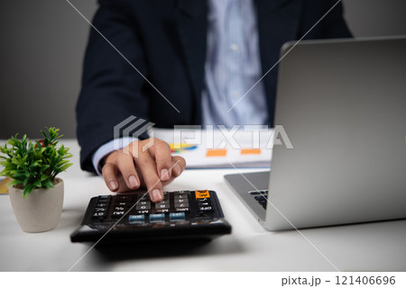 A businessman uses a calculator to perform financial calculations or budget planning. 121406696