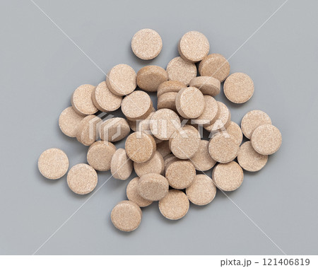 Pile of beige herbal pills on grey close up. Taking dietary supplements and vitamin 121406819