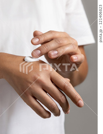 Woman in white t-shirt applying cream on hand to care and protect skin closeup 121406823
