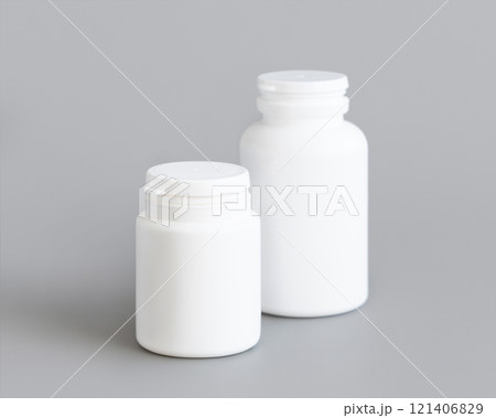 White plastic pill bottles closeup against grey, mockup. Healthcare concept, herbal supplements White plastic pill bottles closeup against grey, mockup. Healthcare concept, herbal supplements 121406829