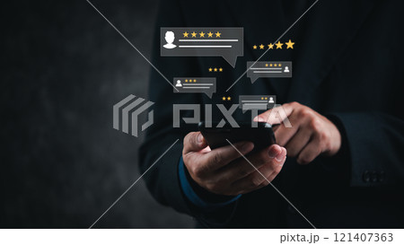 A hand holds a smartphone with floating review icons, symbolizing customer feedback on a digital platform. 121407363