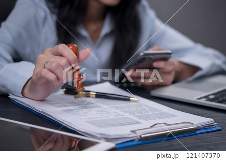 Woman stamping approval on financial, banking, or investment documents at his desk official paperwork. rubber stamp with contract law and business documentation for legal agreements financial 121407370
