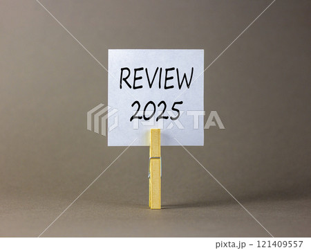 Planning review 2025 new year symbol. Concept words Review 2025 on beautiful white paper on wooden clothespin. Beautiful grey background. Business review 2025 new year concept. Copy space. 121409557