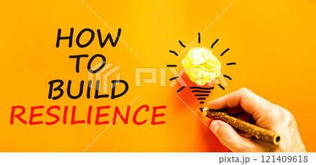 How to build resilience symbol. Concept words How to build resilience on beautiful orange paper. Beautiful orange background. Businessman hand. Business and how to build resilience concept. Copy space How to build resilience symbol. Concept words How to build resilience on beautiful orange paper. Beautiful orange background. Businessman hand. Business and how to build resilience concept. Copy space 121409618
