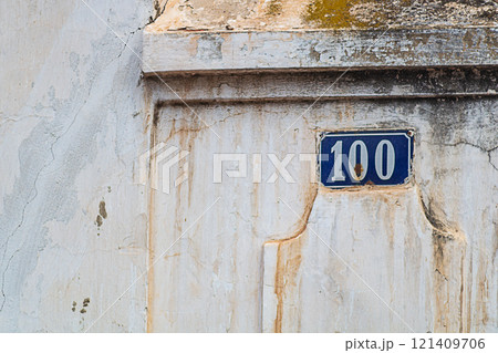 Old, slightly dirty street sign indicating the house number. The coating of the wall and the tablet, under the influence of time, became covered with cracks and rust. Concept of aging and destruction Old, slightly dirty street sign indicating the house number. The coating of the wall and the tablet, under the influence of time, became covered with cracks and rust. Concept of aging and destruction 121409706