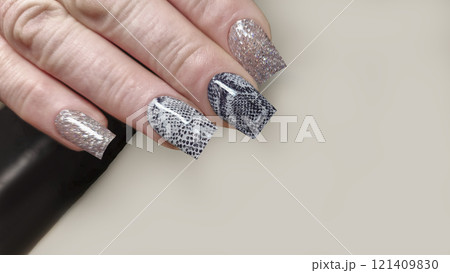 Acrylic nail extensions with a snake design and glitter gel polish. Manicure Acrylic nail extensions with a snake design and glitter gel polish. Manicure 121409830