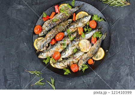 Grilled sardines on a plate with lemon. 121410399