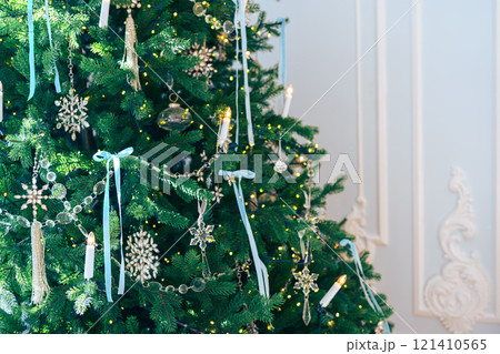 Christmas tree branches adorned with glass ornaments and ribbons on white plaster wall background 121410565