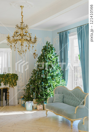Beautifully decorated Christmas tree with gift boxes and vintage couch in elegant room 121410566