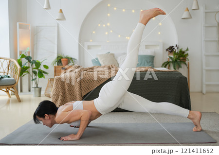 Yoga fitness workout training. Woman practicing yoga at home. Woman doing sports exercise on yoga mat on floor indoor. Girl in sportswear have training workout for weight loss. Sport and fitness 121411652
