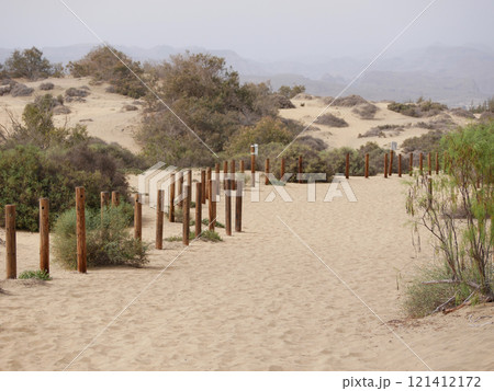 A walking trail fenced with wooden posts in a sand desert dune in Maspalomas, Gran Canaria A walking trail fenced with wooden posts in a sand desert dune in Maspalomas, Gran Canaria 121412172