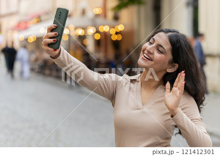 Indian woman blogger taking selfie on smartphone video call online with subscribers on city street Indian woman blogger taking selfie on smartphone video call online with subscribers on city street 121412301