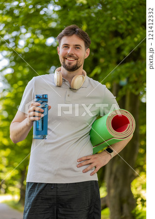 Athletic fitness sport runner man with yoga mat drinking water from bottle after training exercise 121412332