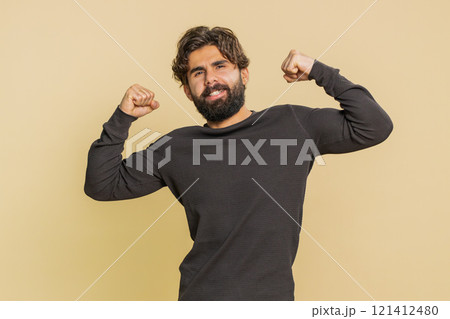 Fit sporty man showing biceps and looking confident, feeling power strength on beige background 121412480