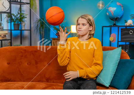 Teenager boy on home sofa actively enjoying playing with basketball bouncing ball trying to catch it Teenager boy on home sofa actively enjoying playing with basketball bouncing ball trying to catch it 121412539