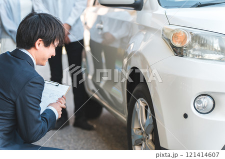 自動車購入・査定・買取にきた夫婦を接客するセールスマンの若いアジア人男性 自動車購入・査定・買取にきた夫婦を接客するセールスマンの若いアジア人男性 121414607