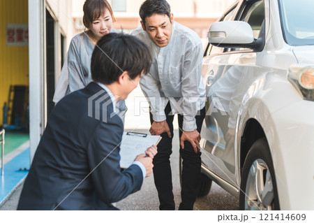 自動車購入・査定・買取にきた夫婦を接客するセールスマンの若いアジア人男性 121414609