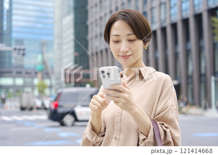 外でスマートフォンを操作する女性 121414668