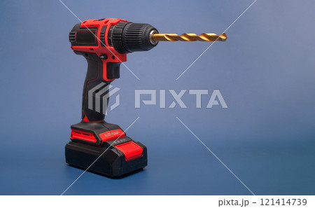 electric cordless screwdriver with a metal drill on a blue. isolate 121414739