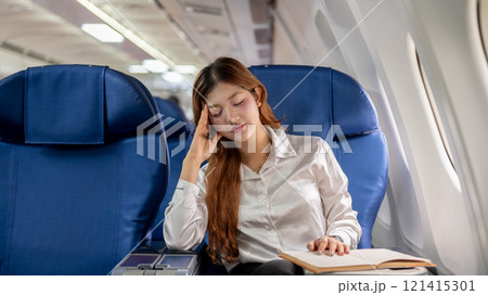 A tired Asian businesswoman feels dizzy from reading during the long flight, traveling abroad. 121415301