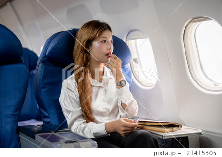 An unwell Asian woman takes airsick medicine during the flight, feeling dizzy, while flying abroad. An unwell Asian woman takes airsick medicine during the flight, feeling dizzy, while flying abroad. 121415305