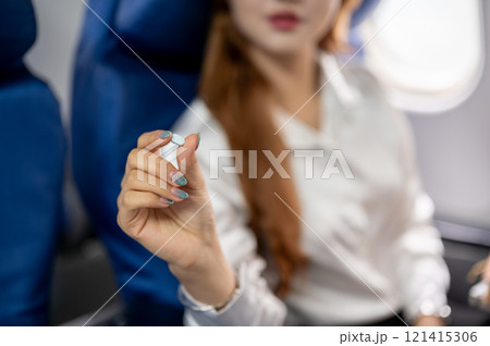 A close-up of a female passenger showing a medicine to the camera while sitting in an airplane. A close-up of a female passenger showing a medicine to the camera while sitting in an airplane. 121415306