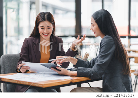 Two colleagues review financial documents with charts and graphs during a business meeting, focusing on analysis and decision-making. 121415517