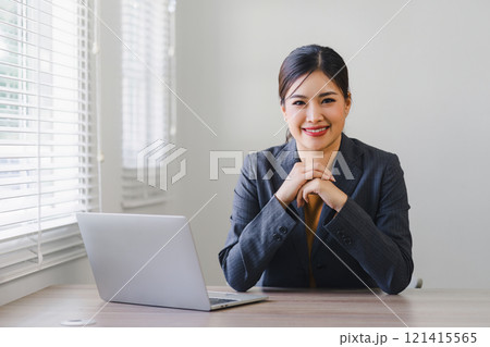 Portrait of professional millennial Asian businesswoman in casual attire analyzing financial data on her laptop computer in the office. Portrait of professional millennial Asian businesswoman in casual attire analyzing financial data on her laptop computer in the office. 121415565