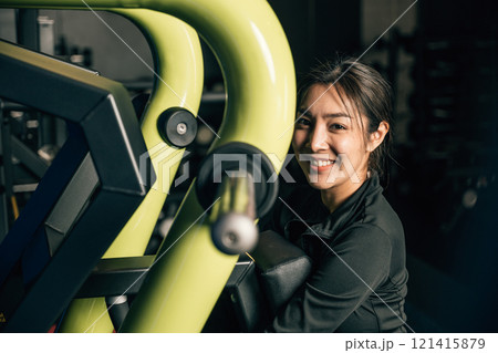 Portrait of beautiful Asian young woman performing squats on a gym machine, female working out with rowing machine at crossfit fitness, healthy lifestyle concept 121415879