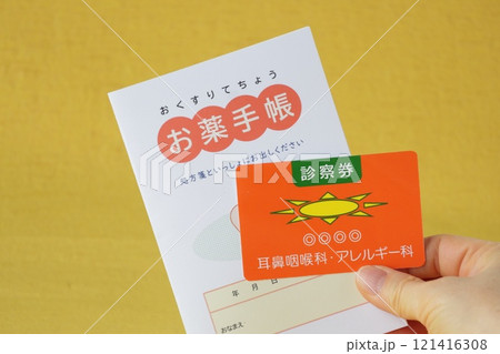 手に持ったお薬手帳と診察券 121416308