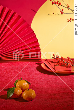 Front close up view on red new year table in asian style. Fresh tangerine, lucky money envelope, paper fan and red flower decoration on table, blank space in center for adding product Front close up view on red new year table in asian style. Fresh tangerine, lucky money envelope, paper fan and red flower decoration on table, blank space in center for adding product 121417216