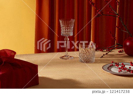 Creative template photo for new year advertising banner design. A new year table setting with wine glasses, porcelain dish, gift box and red flowers. Vacant space in center for product presentation Creative template photo for new year advertising banner design. A new year table setting with wine glasses, porcelain dish, gift box and red flowers. Vacant space in center for product presentation 121417238